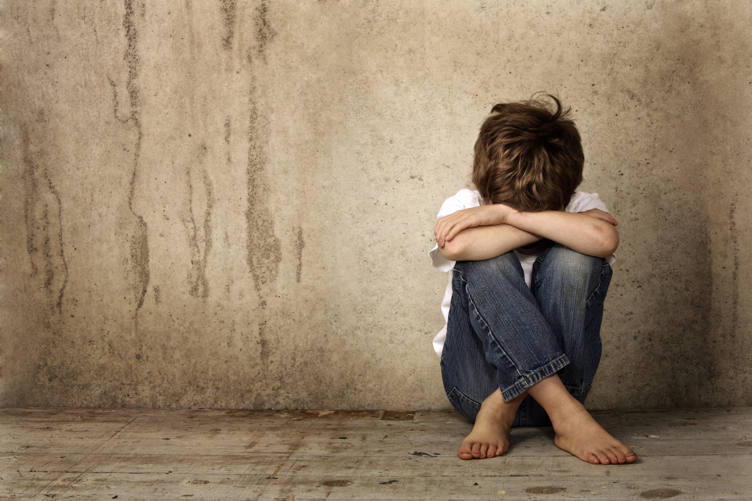 A young boy hides his face in his knees after being victimized by an internet sex crime
